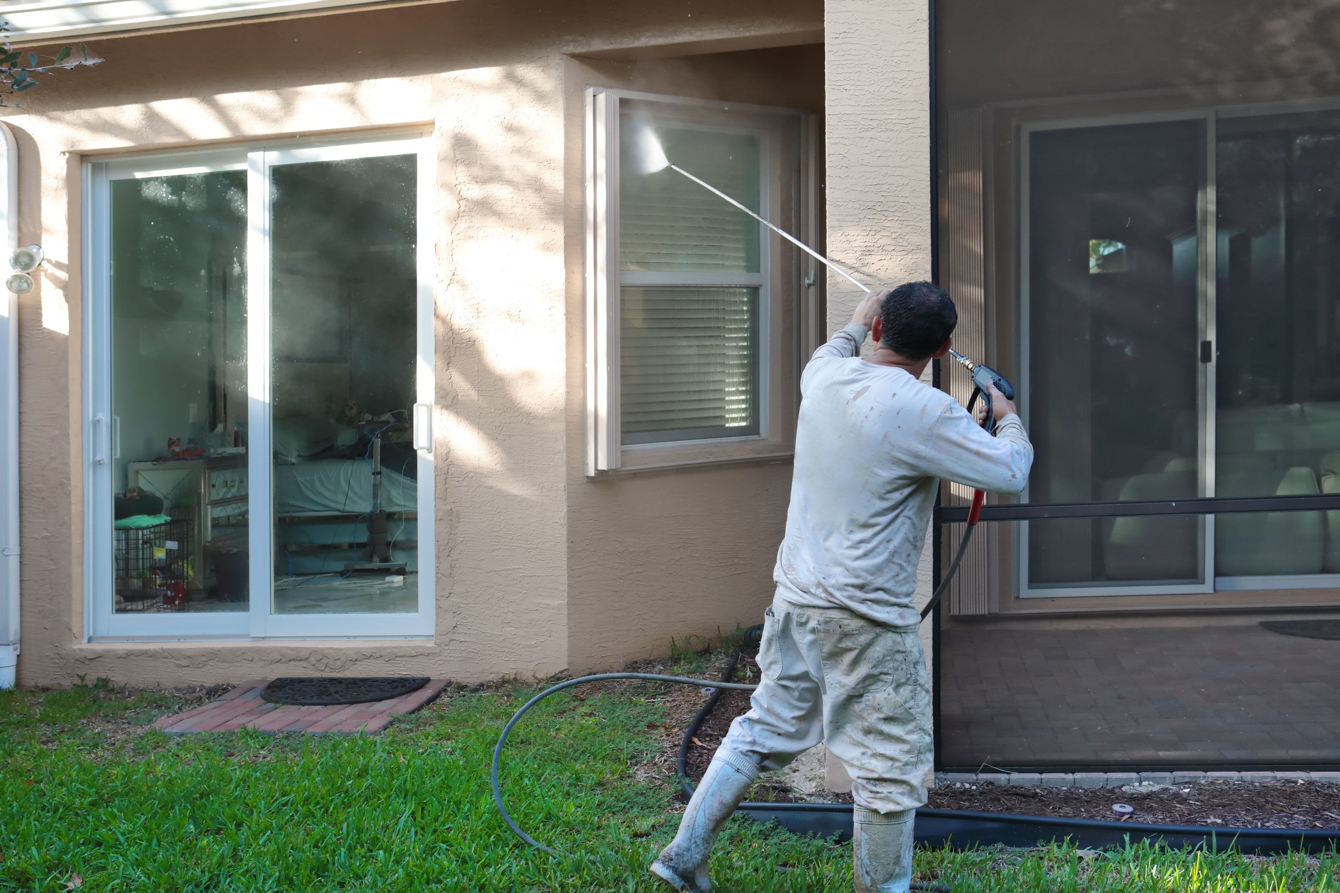 Series:Hispanic male house worker power washing back of upscale home